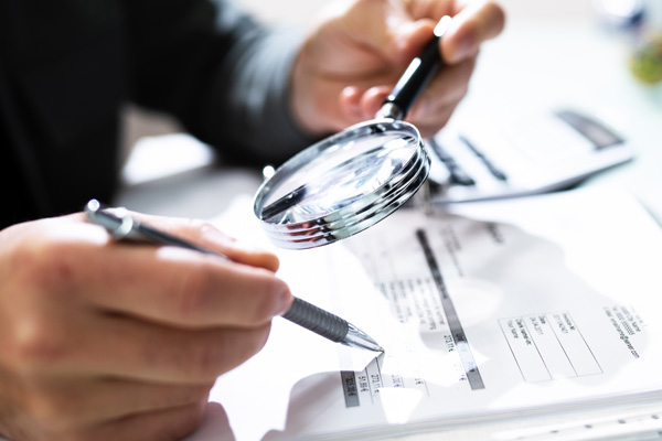 subrogation examining paperwork with pen and magnifying glass